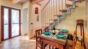 A dining area with a wooden table set for four, a staircase, and a door leading outside. - La Piccola Casa Dell'uva Fragola Next to the Lake (Meina)