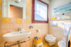 Un baño con lavamanos, inodoro y ventana.