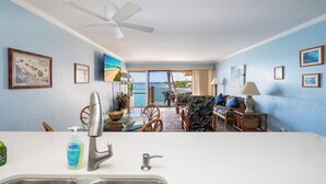 A hotel room with a kitchen area, dining space, and a balcony with a view. - Sea Village 3312: Oceanfront condo in Kailua-Kona, with stunning views! (Kailua-Kona)