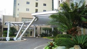 A modern building with a covered entrance, a landscaped garden with rocks and plants, and a paved driveway. - South of Market  (Taguig)