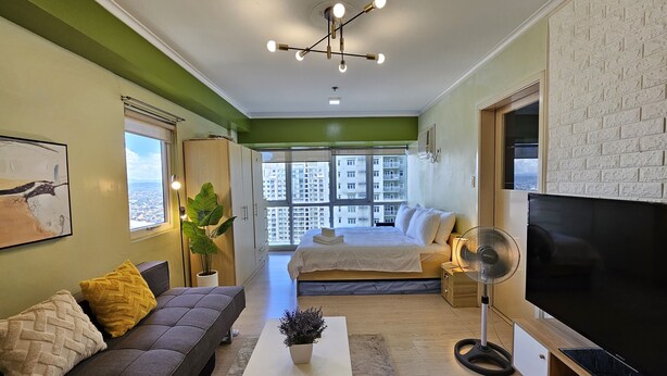 A modern living room with a sofa, a coffee table, a TV, and a bed. - South of Market  (Taguig)