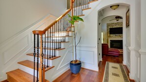 A wooden staircase with black balusters, a potted plant, and a patterned rug on a wooden floor. - High Point Vacation Rental w/ Private Deck! (High Point)