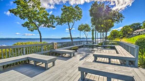 A wooden deck with benches and tables overlooking a body of water. - Gilford Townhome w/ Lakefront Beach & Pool Access! (Gilford)