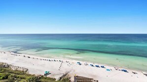 A beach with clear turquoise waters, white sand, and several beach umbrellas. - One Seagrove Place 1201 (Santa Rosa Beach)