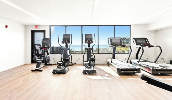 A fitness room with cardio machines and a large window with a view. - One Seagrove Place 1201 (Santa Rosa Beach)