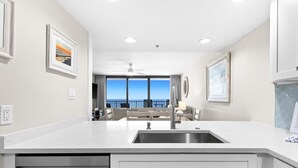 A modern kitchen with a large island, built-in appliances, and a view to the outdoors. - One Seagrove Place 1201 (Santa Rosa Beach)