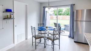 Une cuisine moderne avec une table à manger, des chaises et un réfrigérateur en acier inoxydable.