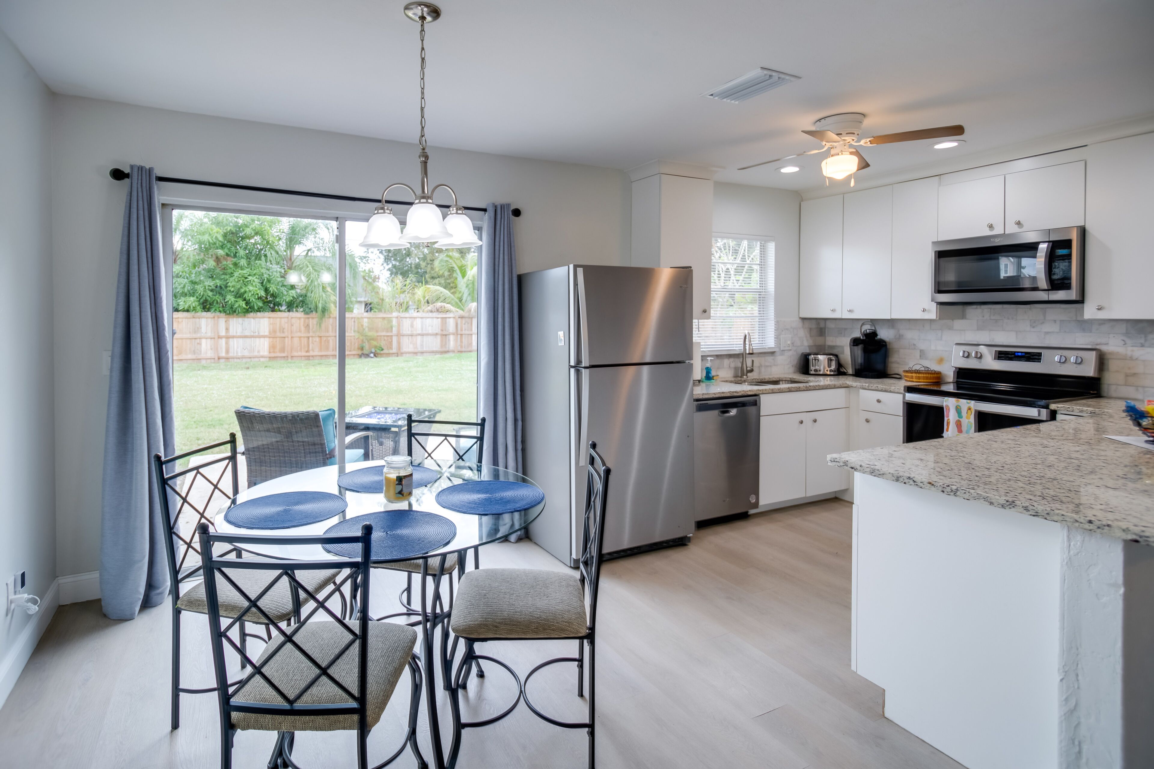 Une cuisine moderne avec un coin repas, des appareils électroménagers en acier inoxydable et une vue sur le jardin arrière.