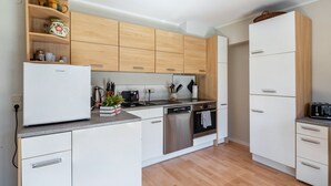 Een moderne keuken met houten kastjes, een witte koelkast, roestvrijstalen apparatuur en een aanrecht met verschillende voorwerpen.