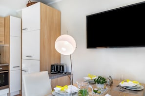 A modern kitchen with white cabinets, a toaster, and a dining table set for two with plates, glasses, and a pitcher. - Holiday Apartment "Efzeglück" with Outdoor Pool, Shared Terrace and Wi-Fi (Homberg (Efze))