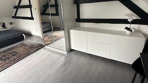 Et moderne soveværelse med en hems, indbygget skab og et stort spejl.