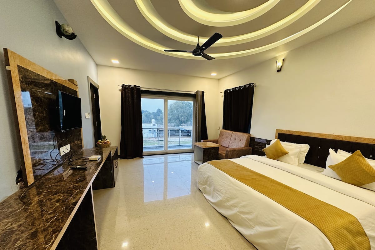 Une chambre d’hôtel moderne dotée d’un grand lit, d’un téléviseur à écran plat, d’une coiffeuse en marbre et offrant une vue sur l’extérieur.