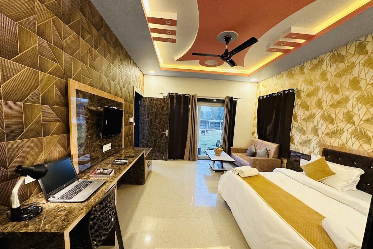 Une chambre d’hôtel équipée d’un lit, d’un bureau avec un ordinateur portable, d’une télévision et d’un ventilateur de plafond.