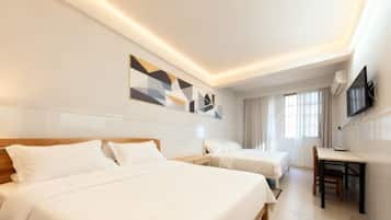 A hotel room with two beds, a desk, and a television.