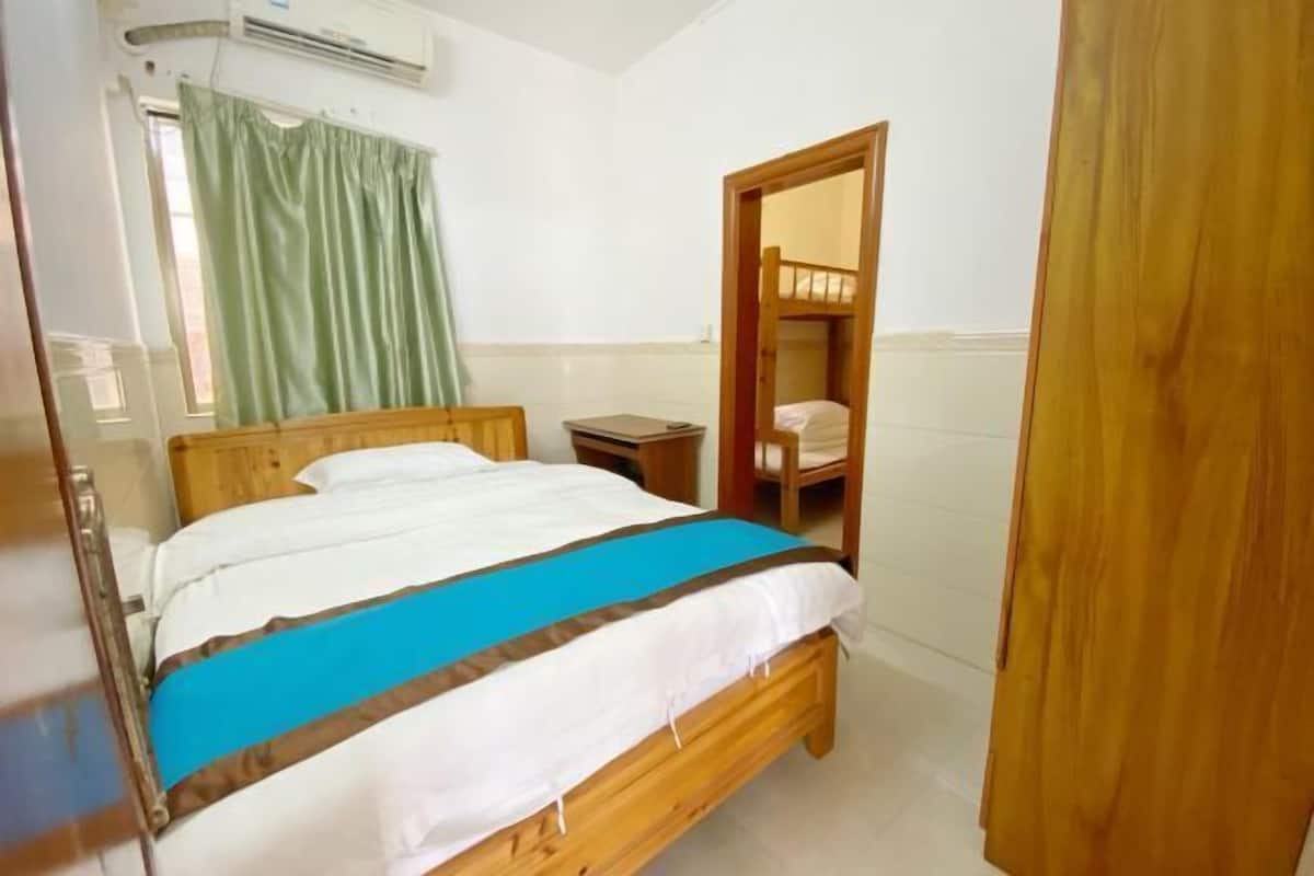 A bedroom with a wooden bed, a bedside table, a mirror, and a window with curtains.