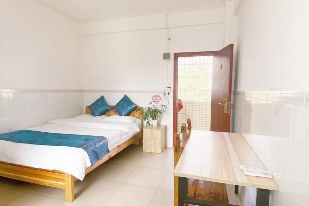 A bedroom with a bed, bedside table, and a door leading to another room.