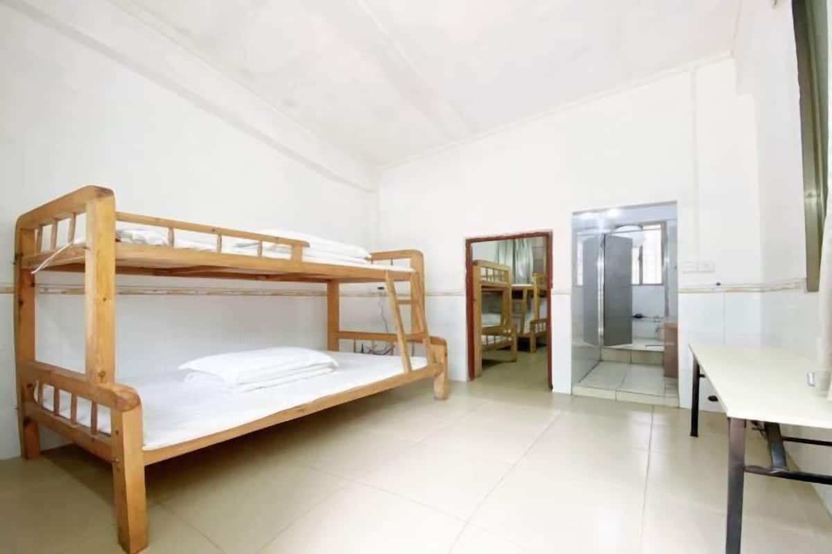 A bunk bed in a room with a desk and a mirror.