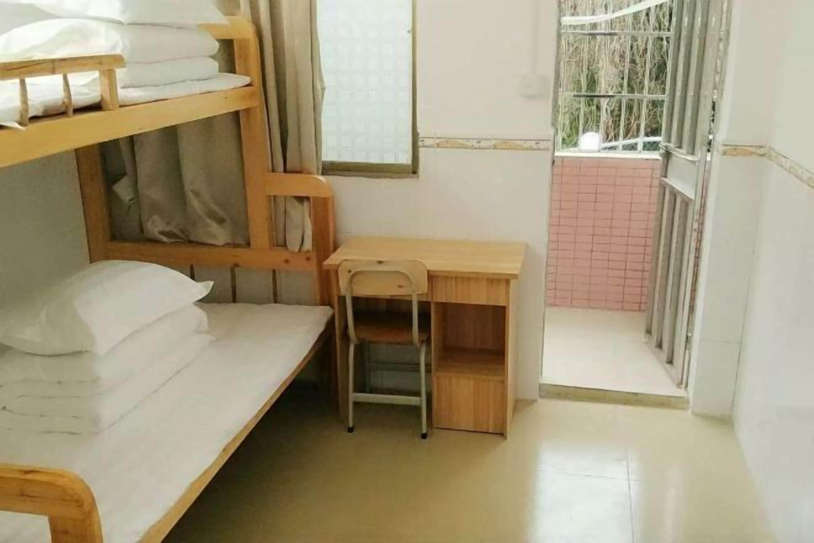 Een slaapzaal met stapelbedden, een bureau en een stoel.