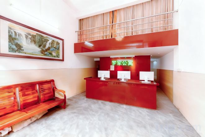 A reception area with a red desk, a bench, and a painting on the wall.
