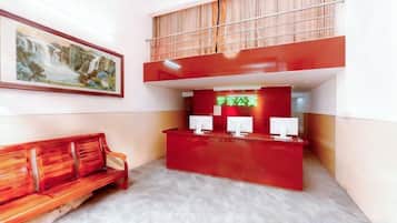 A reception area with a red desk, a bench, and a painting on the wall.