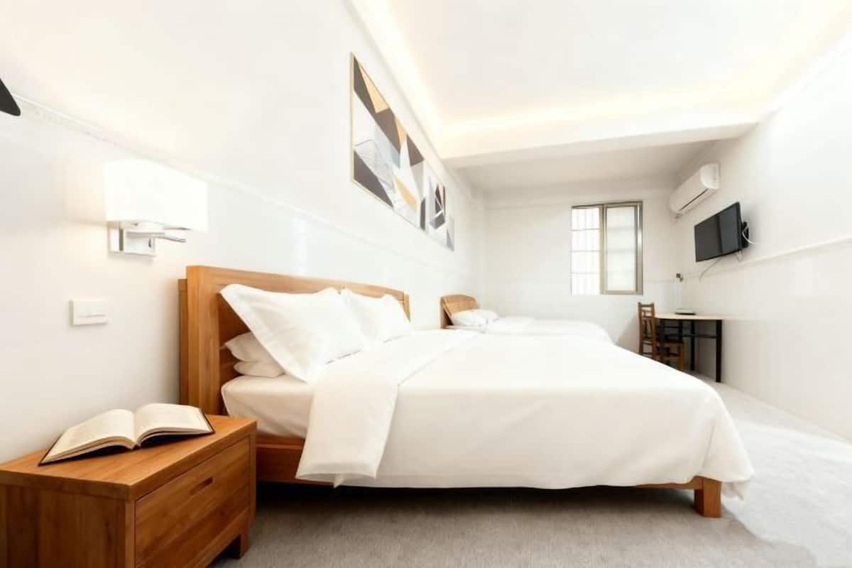 A bedroom with a bed, bedside table, and a TV mounted on the wall.