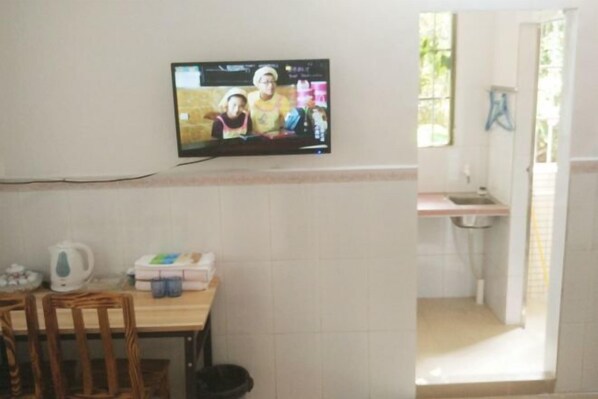 A room with a television mounted on the wall, a table with chairs, a kitchen area with a sink, and a window. - Luojia Apartment (The Sixth Affiliated Hospital of Sun Yat-sen University) (Guangzhou)
