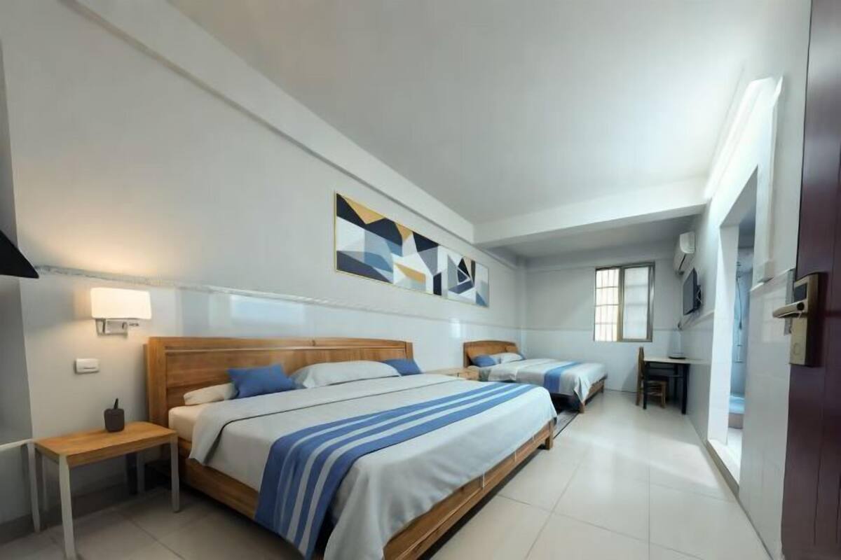 A hotel room with a large bed, a smaller bed, a desk, and a chair.