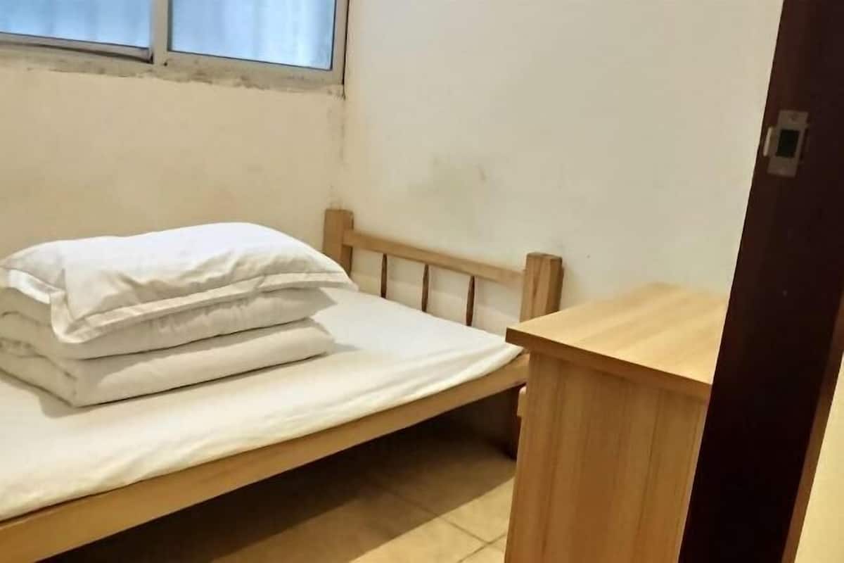 A small, single-bed room with a wooden headboard and a wooden nightstand.