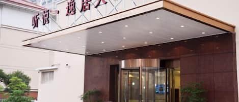 A hotel entrance with a covered walkway, glass doors, and potted plants.