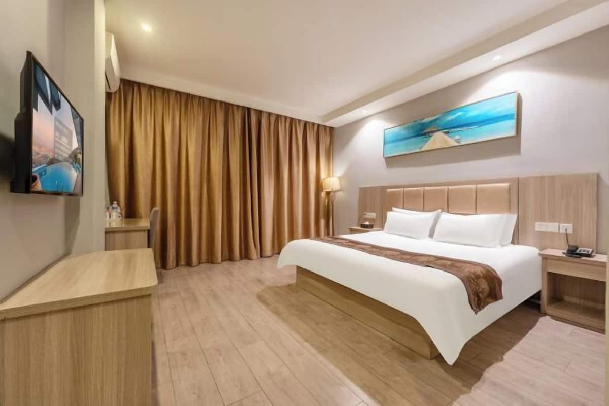 Habitación de hotel con una cama grande, un escritorio, un televisor y un cuadro en la pared.