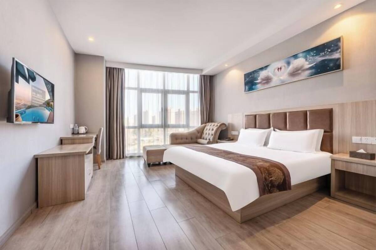 Una habitación de hotel moderna con una cama grande, un escritorio y vistas a la ciudad.