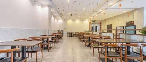 A restaurant with multiple tables and chairs, a tiled floor, and a ceiling with hanging decorations.