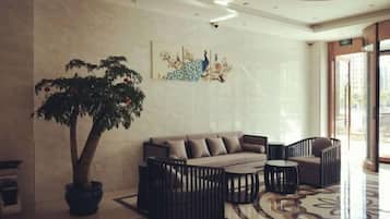 A lobby with a sofa set, a coffee table, a potted plant, and a wall with artwork.