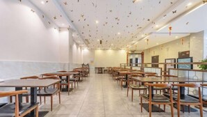 A spacious restaurant with wooden tables and chairs, a tiled floor, and a ceiling decorated with hanging bird ornaments. - Tingyue Yiju Hotel (Shanghai)