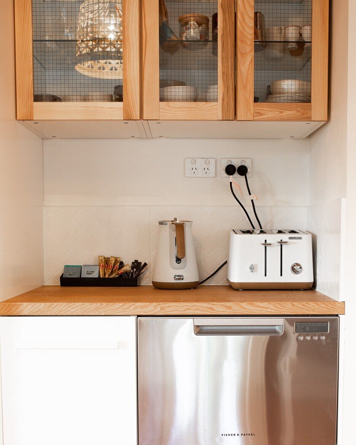 Een keuken met houten kastjes, een broodrooster, een waterkoker en een vaatwasser.
