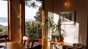 A cozy reading nook with a wooden table, chairs, and a bookshelf filled with books. - Birdsong - a cosy cabin with a view (Adventure Bay)