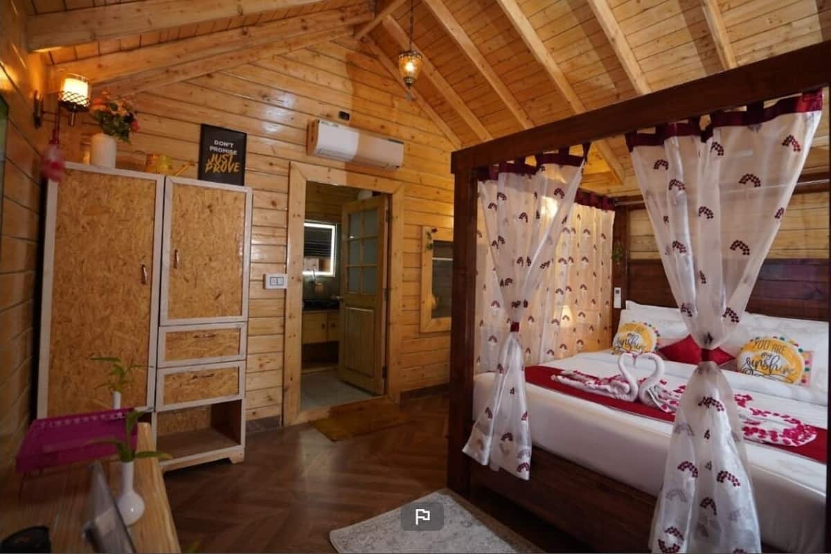 Ein holzgetäfeltes Zimmer im Chalet-Stil mit einem Bett, einem Holzschrank und einem kleinen Tisch mit einer Vase.