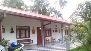 A house with a tiled porch, a bench, a scooter, and potted plants. - Orchid Dream (Bentota)