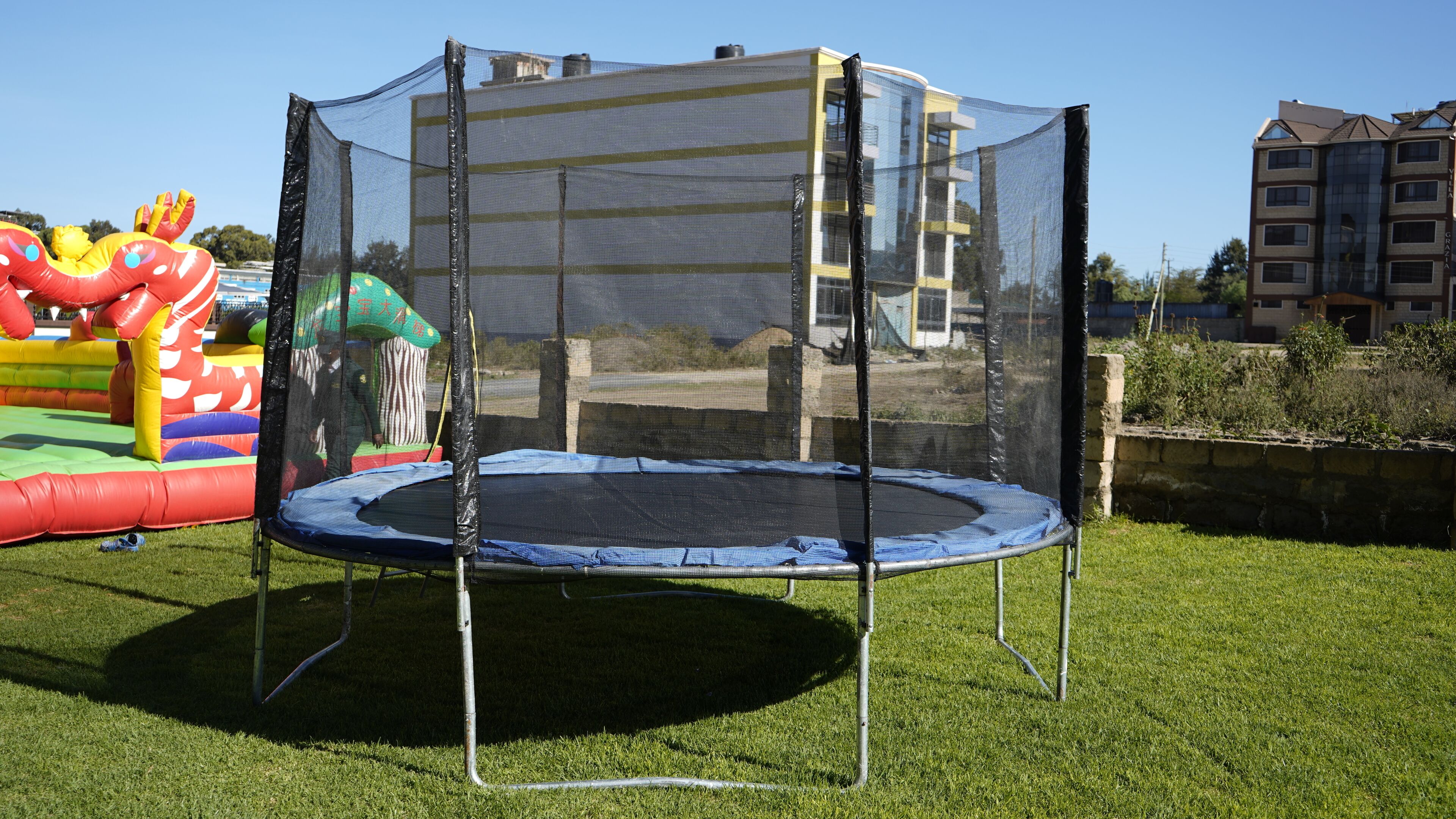 A trampoline with a safety net enclosure in a grassy area.