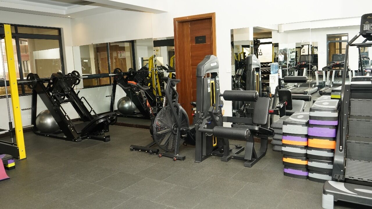 Ein Fitnessstudio mit unterschiedlichen Trainingsgeräten, darunter Laufbänder, Kraftgeräte und Kurzhanteln.