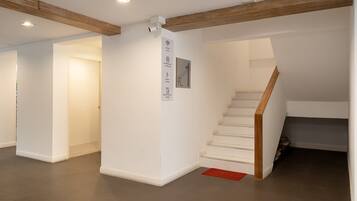 A spacious interior with a staircase, white walls, and a wooden beam ceiling.