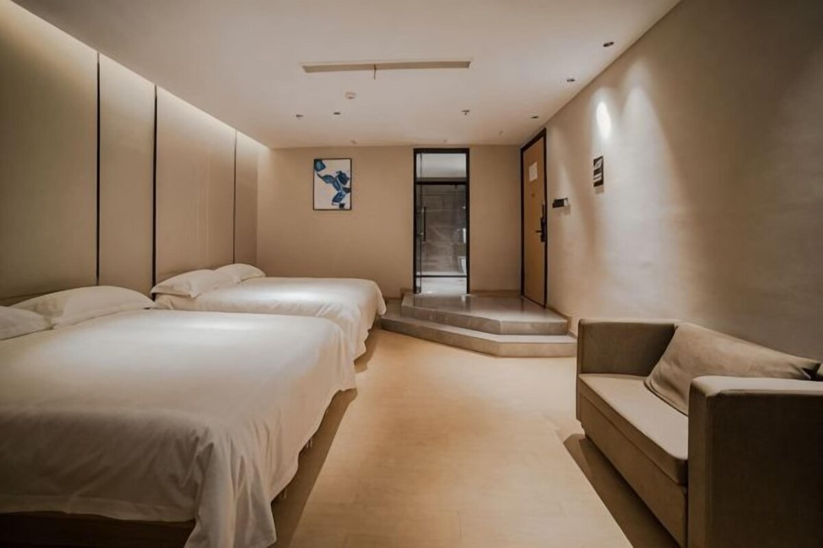 A hotel room with two beds, a sofa, a small staircase, and a door leading to a balcony.