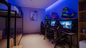 A room with bunk beds, gaming PCs, and a large monitor.