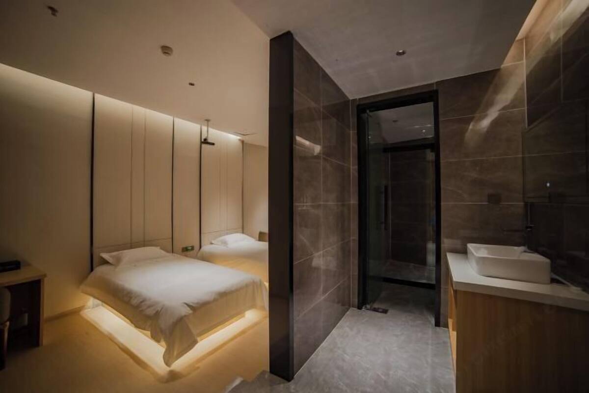 Una habitación de hotel moderna con dos camas, un espejo grande y un área de baño separada.