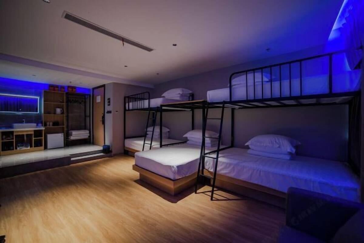 Una habitación con literas, piso de madera, armario empotrado y un escritorio con silla.