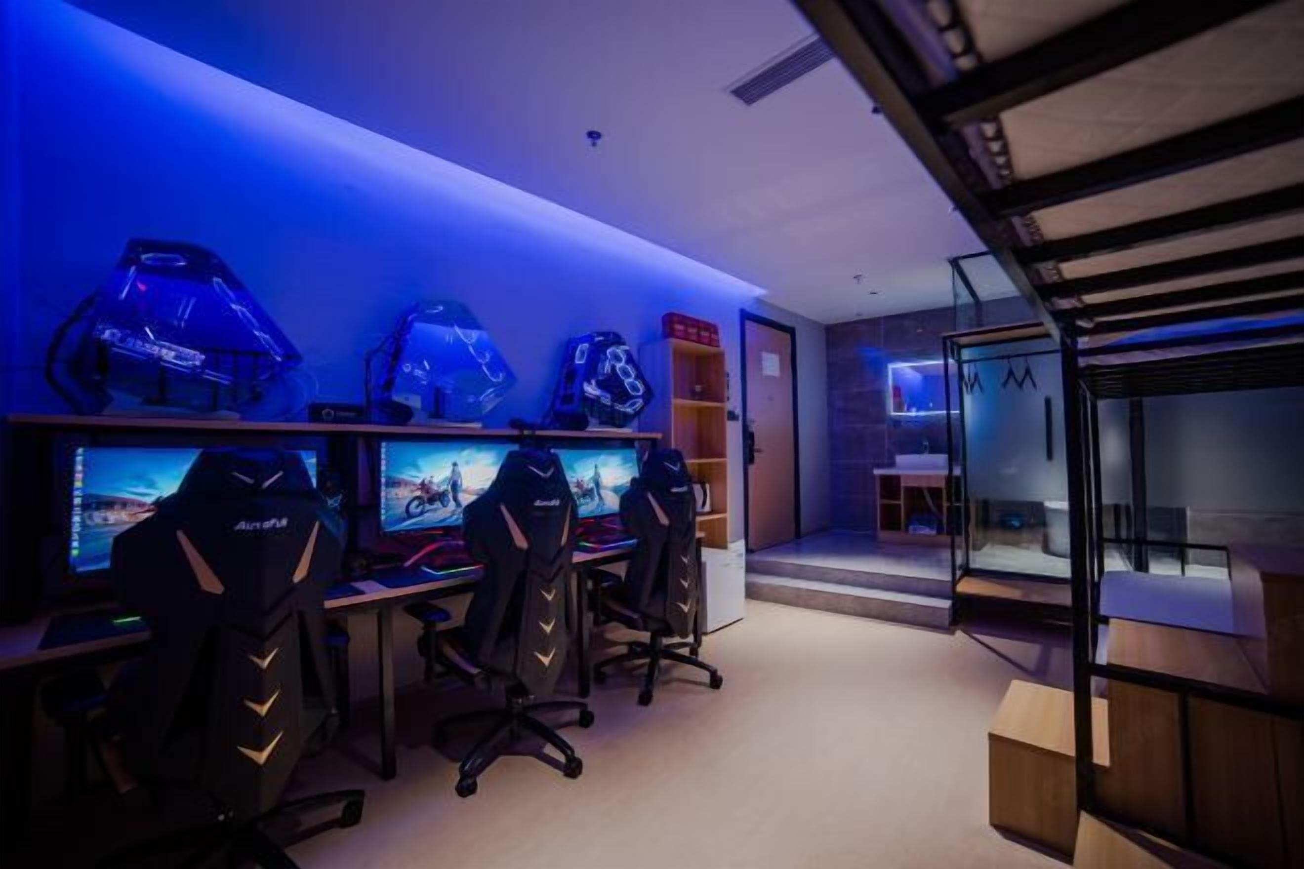 A gaming room with multiple monitors, gaming chairs, and a blue-lit wall.