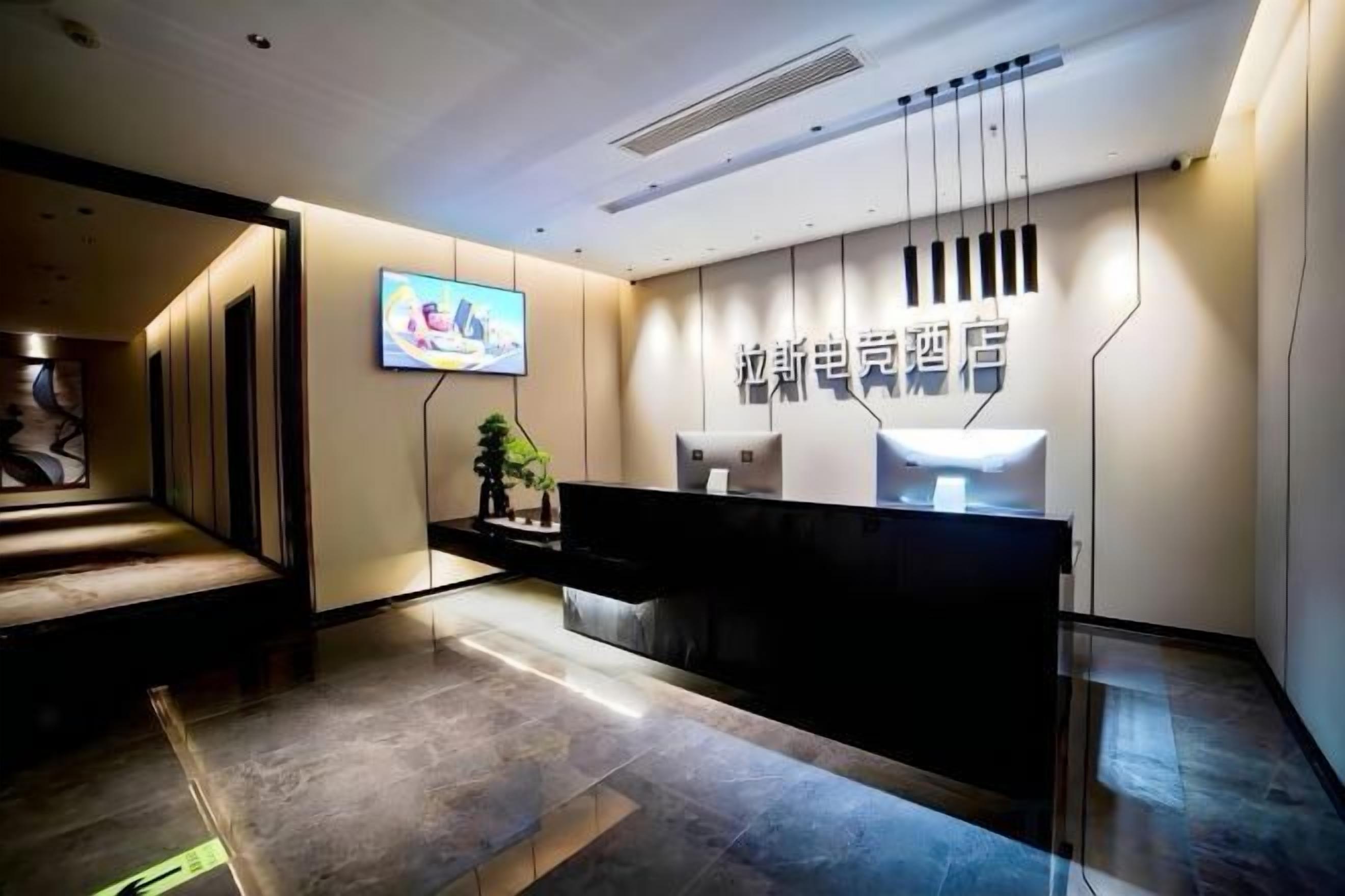 A hotel reception area with a modern design, a reception desk, and a television screen.