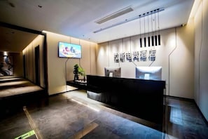 A hotel reception area with a modern design, a reception desk, and a television screen. - Las Esports Hotel (Wenzhou tower store) (Wenzhou)