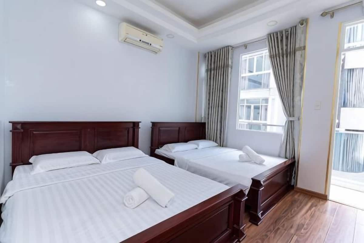 Ein Hotelzimmer mit zwei Betten, einem Fenster mit Vorhängen und einer Klimaanlage.