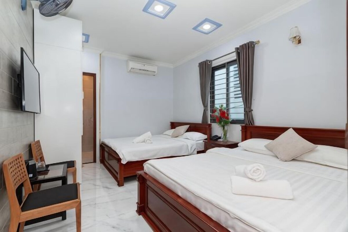 Habitación de hotel con dos camas, televisión, escritorio y una silla.